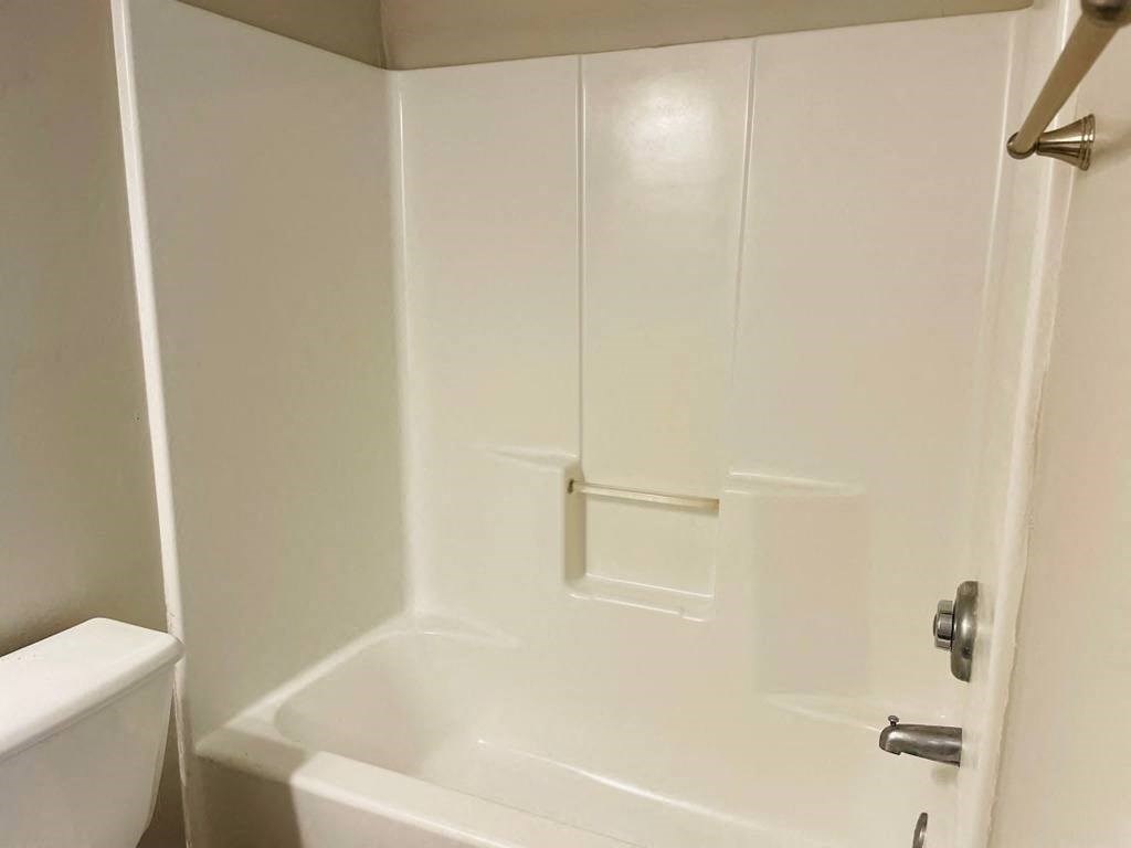 a white bathroom with a shower and a toilet