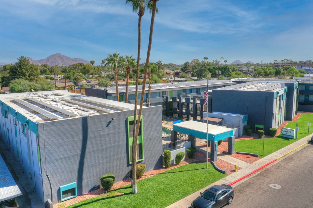 an aerial view of a building with palm trees and a parking lot