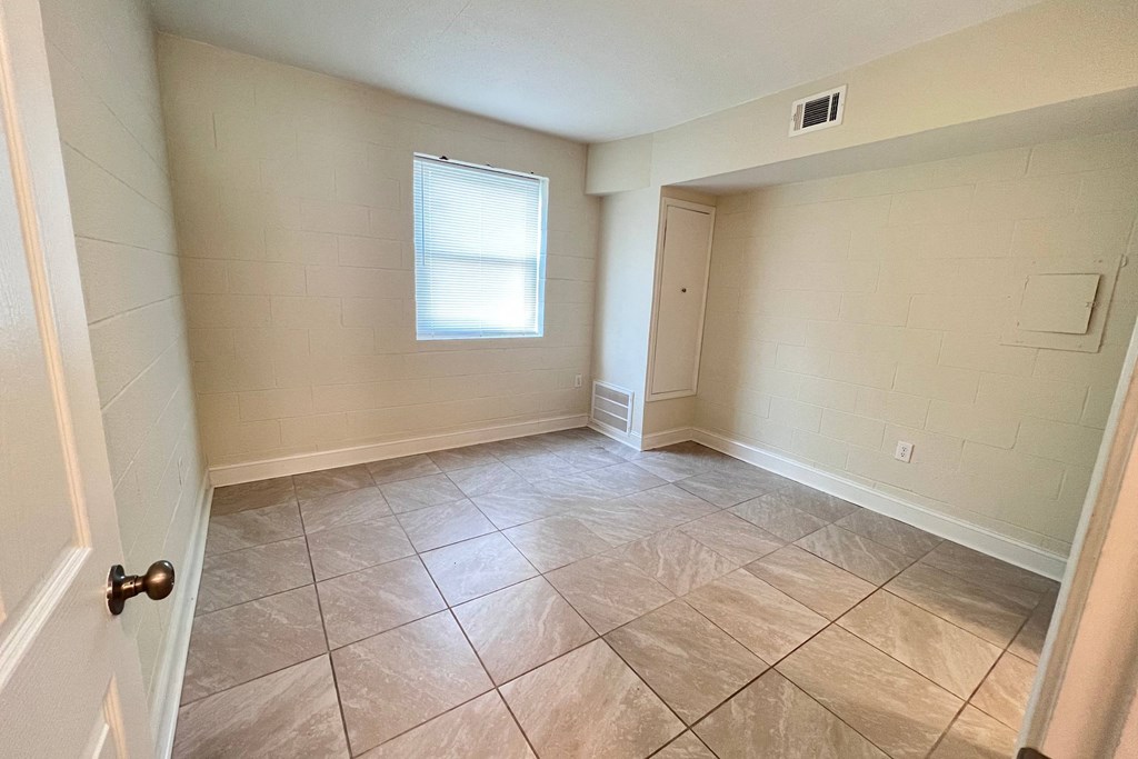 an empty living room with tiled floors and a window