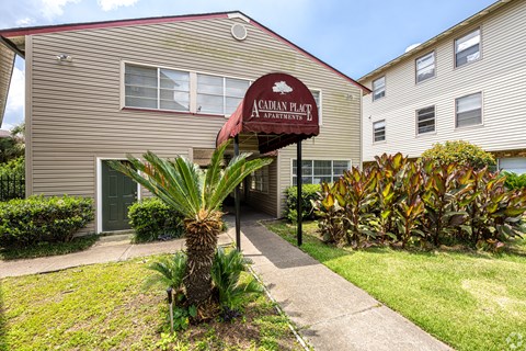 The image shows the front of the Canadian Plait Apartments building with a red awning and a palm tree in the foreground.