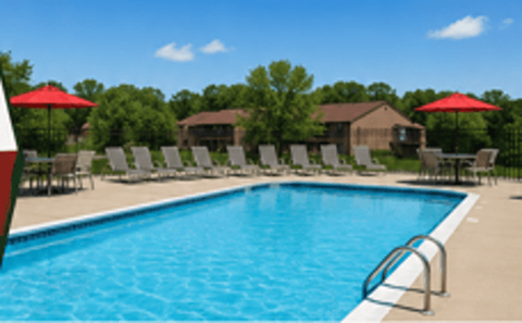 A large swimming pool with a metal ladder and red umbrellas.