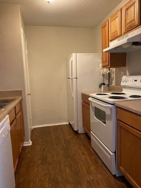 A kitchen with a white fridge, white oven, and white stove.