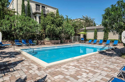 A swimming pool surrounded by blue lounge chairs and trees.