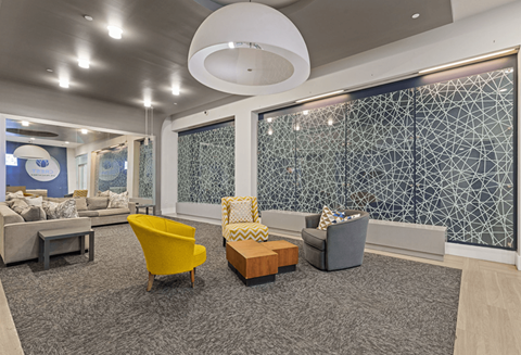 A modern waiting room with a grey carpet and a yellow chair.