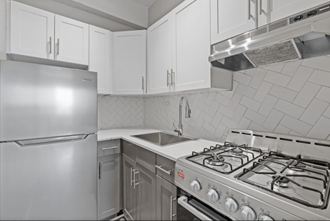 A modern kitchen with a stainless steel refrigerator, oven, and range hood.