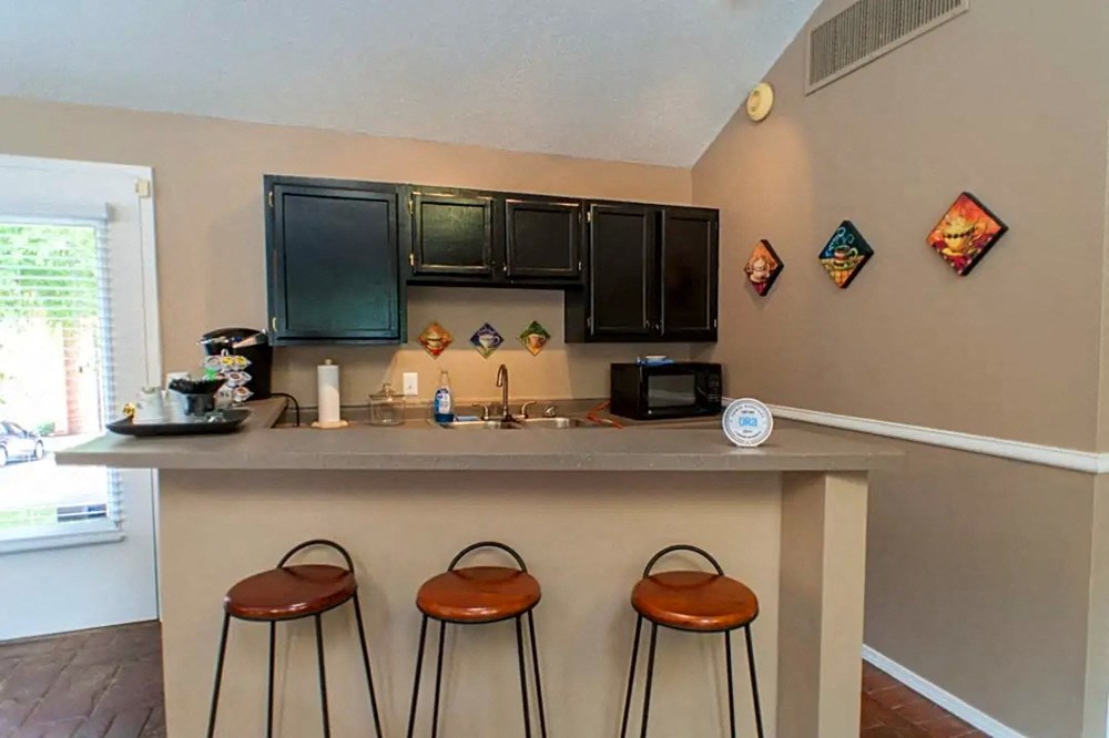 a kitchen with a bar and three stools in front of a counter top