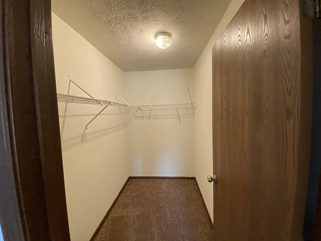 a walk in closet with a wooden door and a white wall with two hanging racks