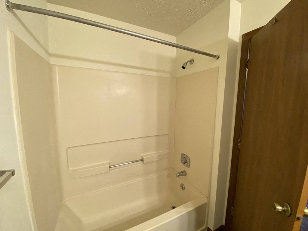 a bathroom with a tub and a shower and a door