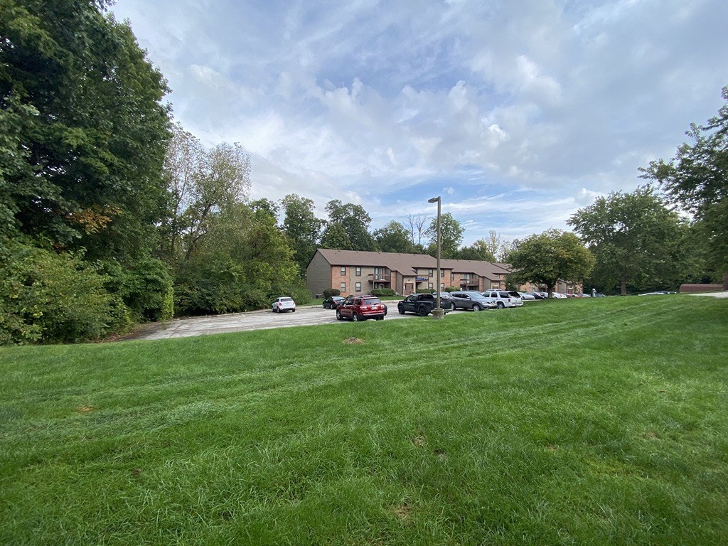 a yard in front of a house with a parking lot