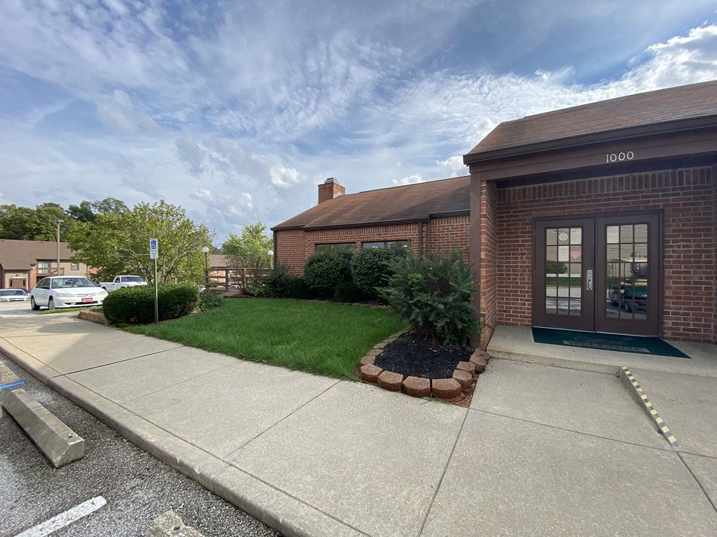 the front of a brick building with a sidewalk and grass