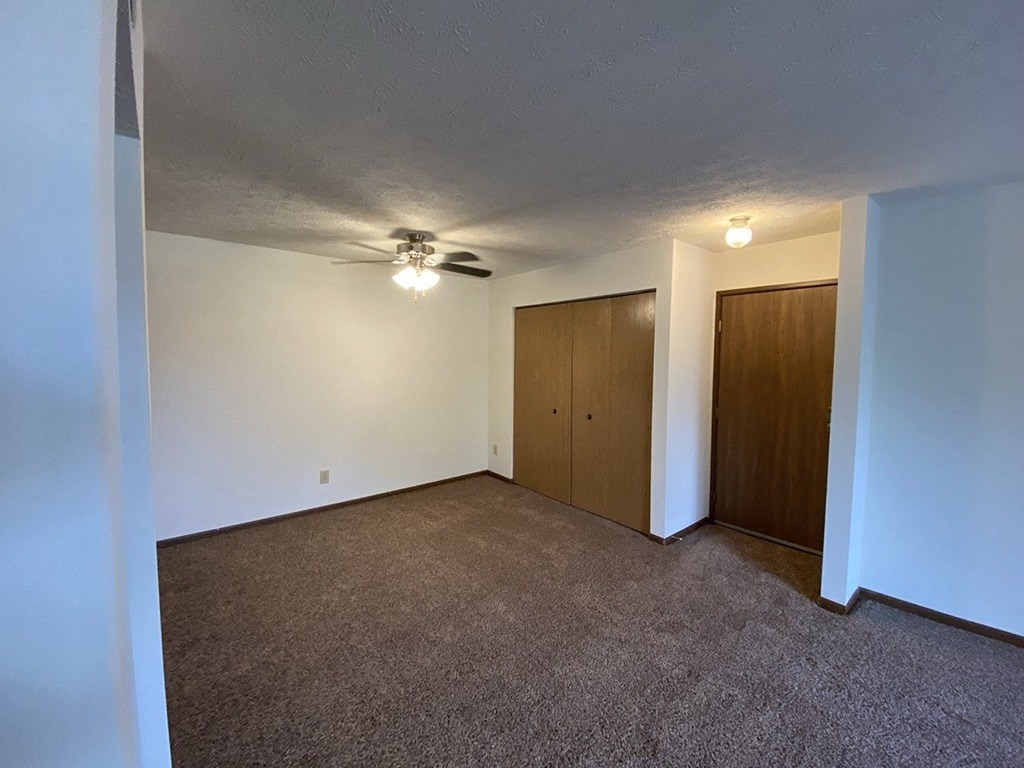 a living room with carpet and a ceiling fan