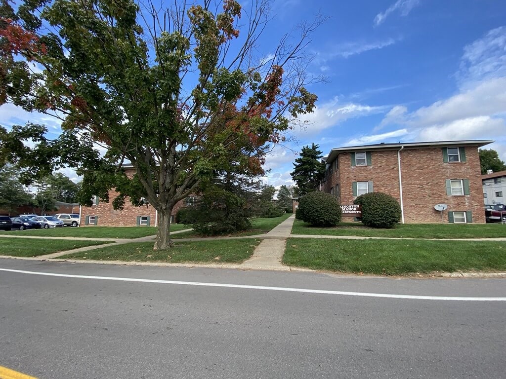 a sidewalk in front of a brick apartment building