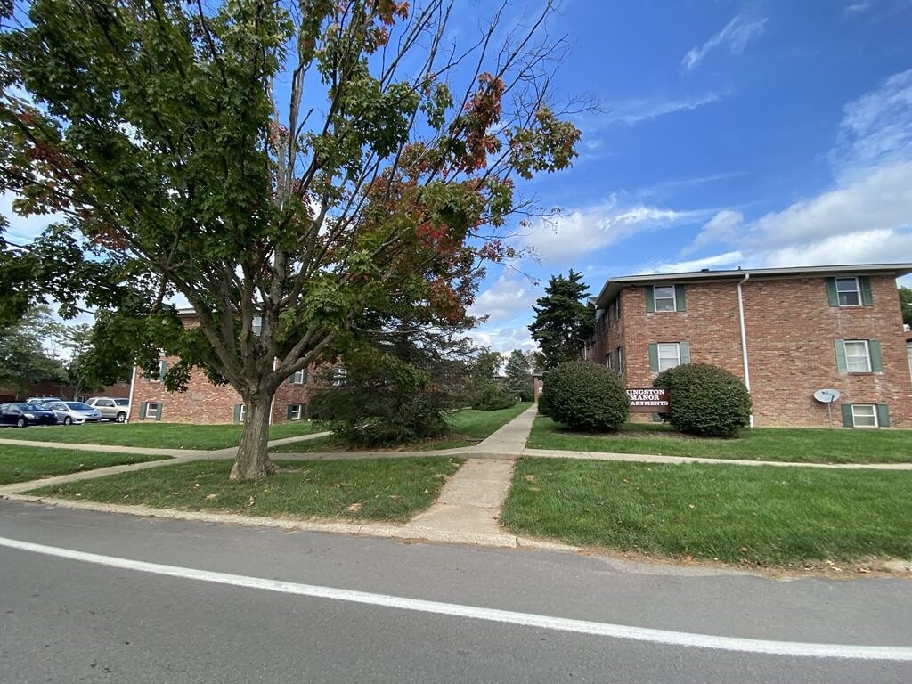 a sidewalk in front of a brick apartment building