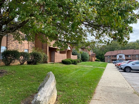 a rock sitting in the grass in front of a building