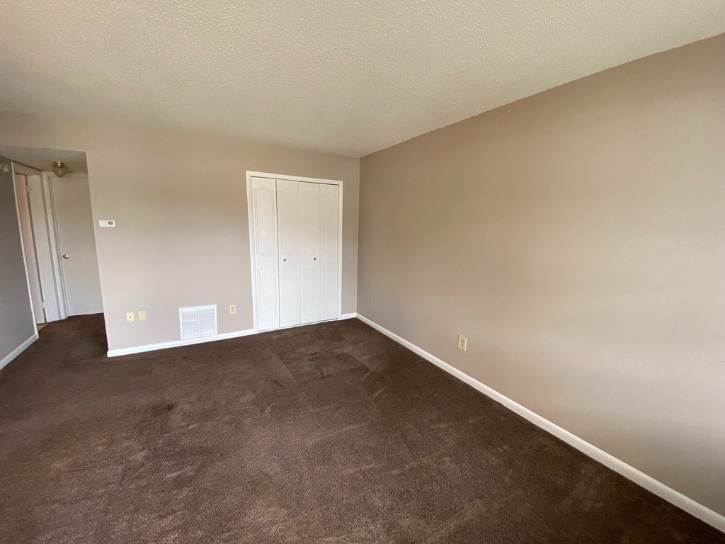 an empty living room with brown carpet and white walls