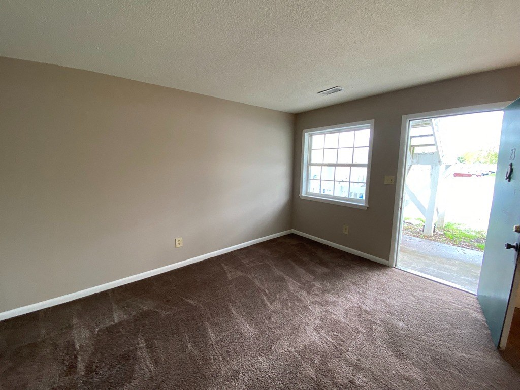 an empty living room with a window and a door