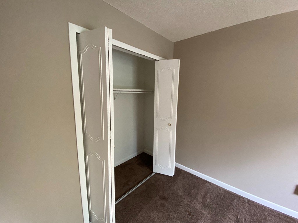 a closet in a empty room with a door open