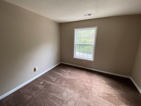 a bedroom with a window and a carpeted floor