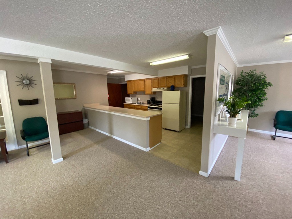 an empty living room with a kitchen and a table