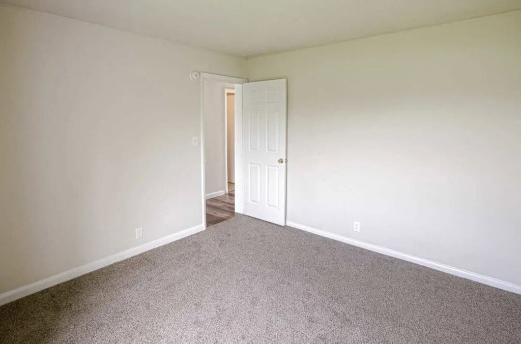 an empty living room with white walls and carpet
