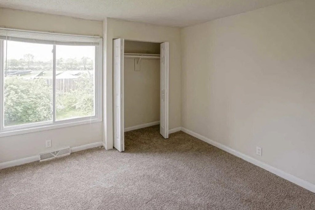 an empty bedroom with a closet and a large window
