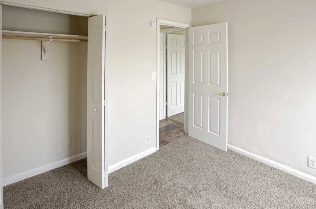 an empty bedroom with a door open to a closet