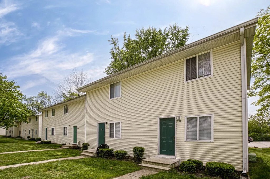 a white house with green doors and a lawn