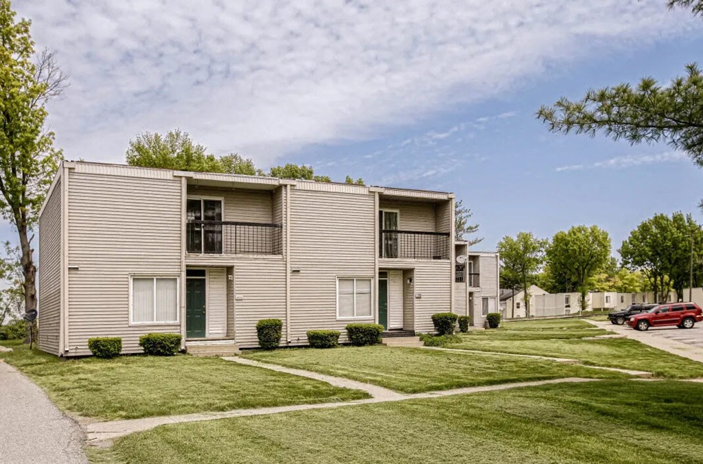 a row of apartment buildings with lawns and trees
