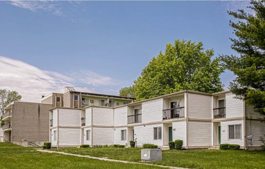 an apartment building with white and gray units and a green lawn