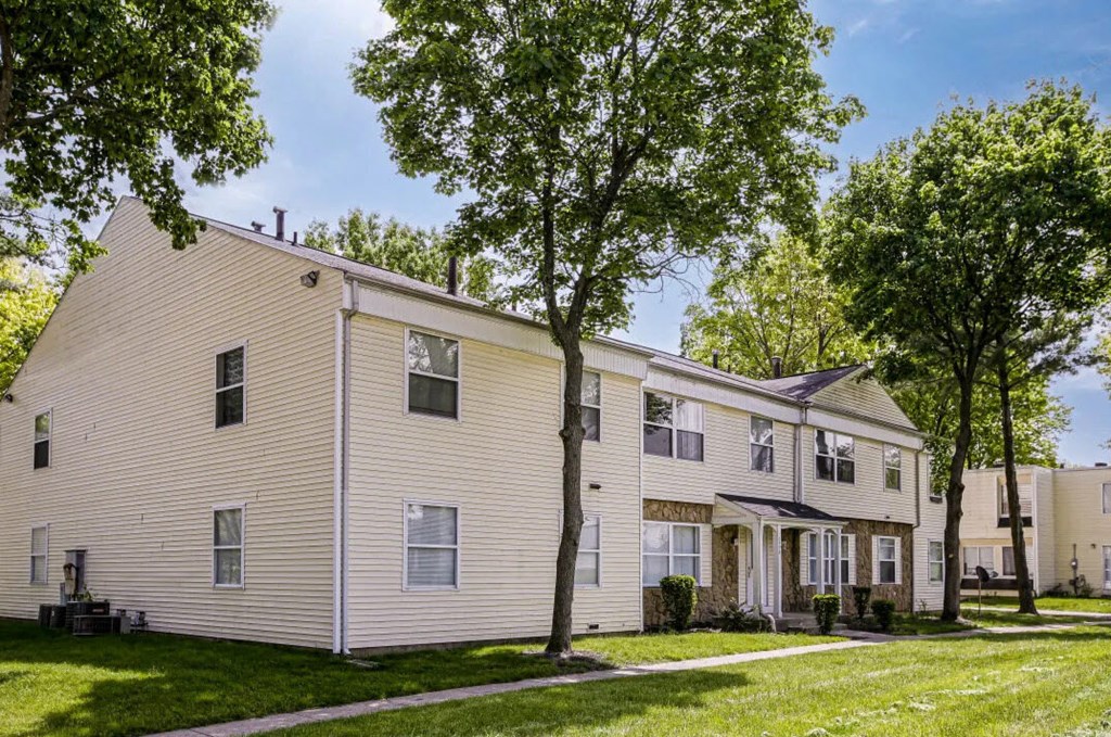 a white house with trees and a sidewalk