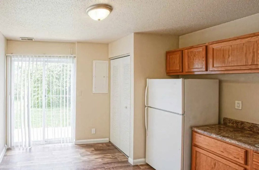 an empty kitchen with a refrigerator and cabinets