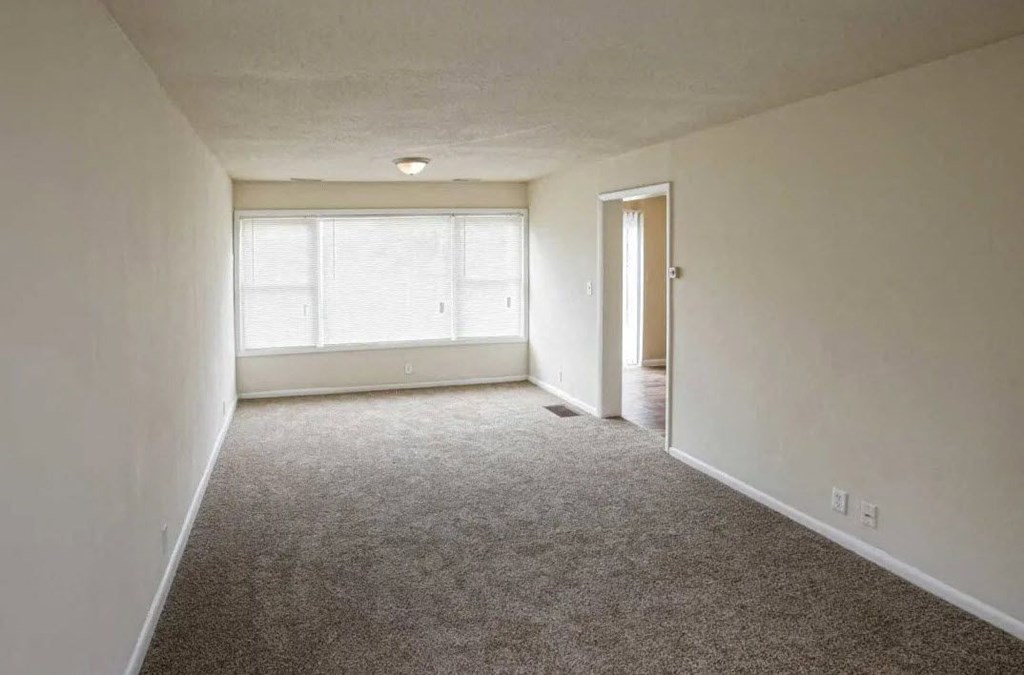 an empty living room with a large window and carpet