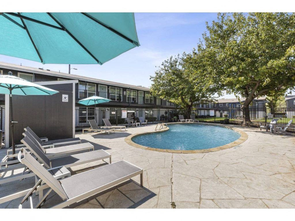 a pool with chairs and umbrellas next to a building