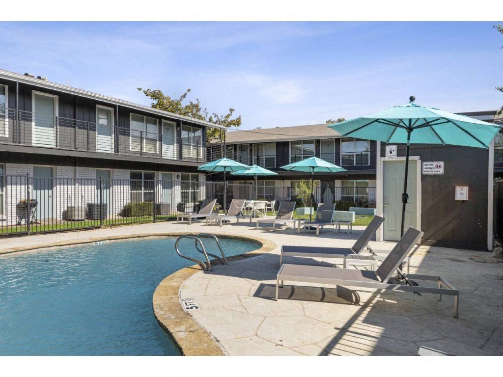 a pool with chairs and umbrellas in front of a building