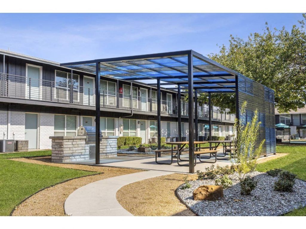 a building with a patio with benches and a blue roof