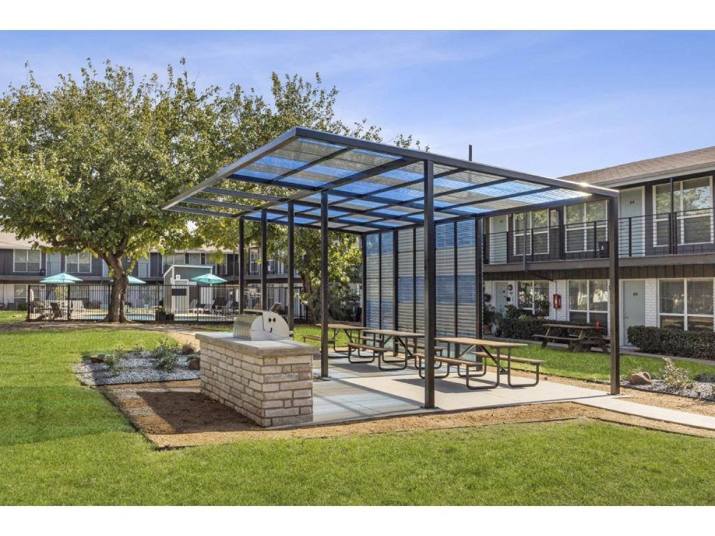 a patio with a pergola and tables in a yard