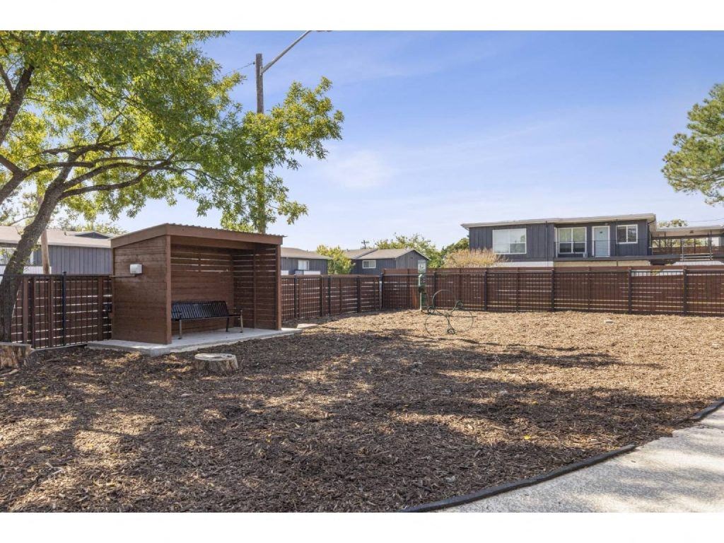 a yard with a fence and houses in the background