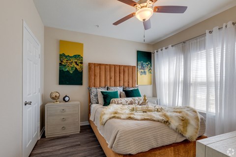 A bedroom with a bed, nightstand, and a ceiling fan.