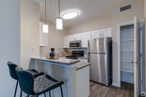 A kitchen with a refrigerator, microwave, oven, and sink.