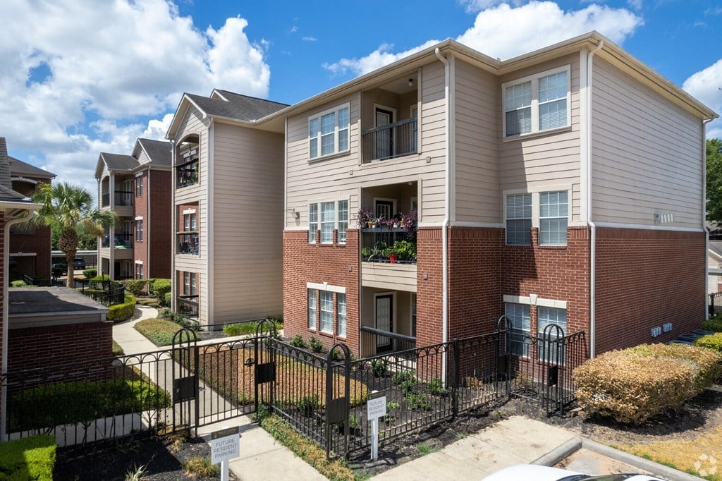 A large apartment complex with a black fence and gate.