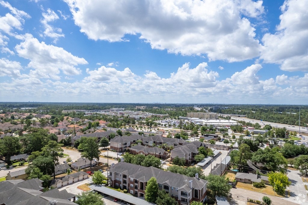 A suburban neighborhood with houses and trees under a blue sky with clouds.