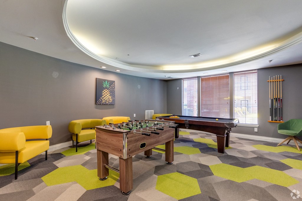 A room with a pool table and chairs.