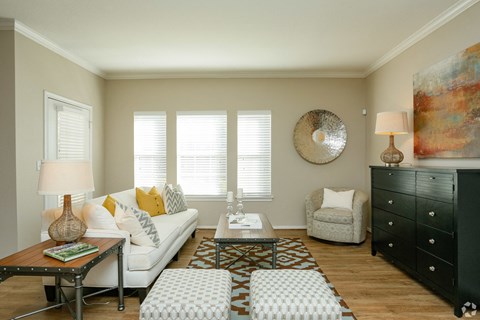 A living room with a white couch, a coffee table, and a large painting on the wall.