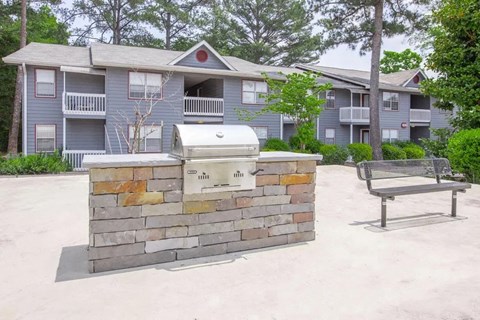 a picnic table and a grill in front of an apartment building