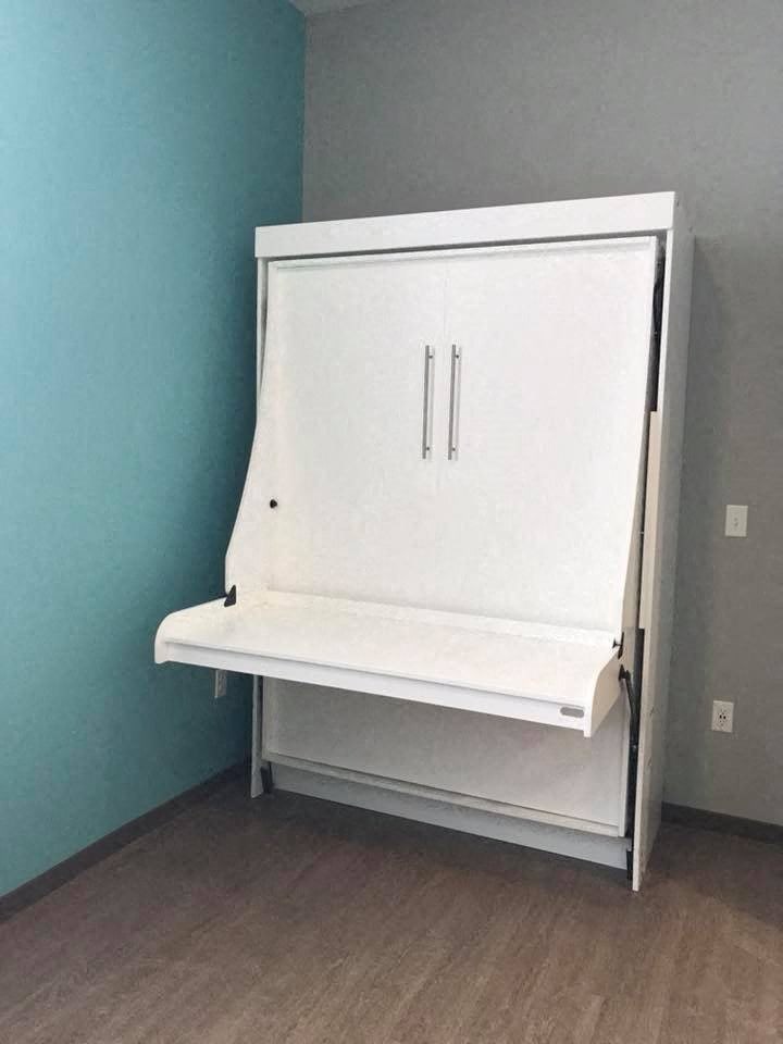 a small white cabinet in a room with a blue wall