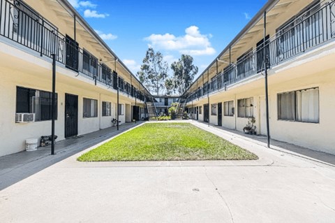 A long row of identical houses with balconies and green lawns.