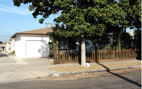 a house with a fence and a tree in front of it