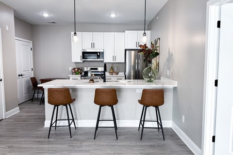 A kitchen with a white island and brown barstools.