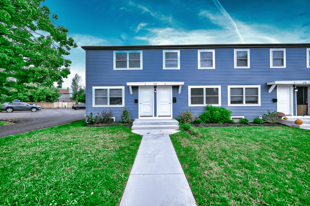 a blue house with a lawn and sidewalk in front of it