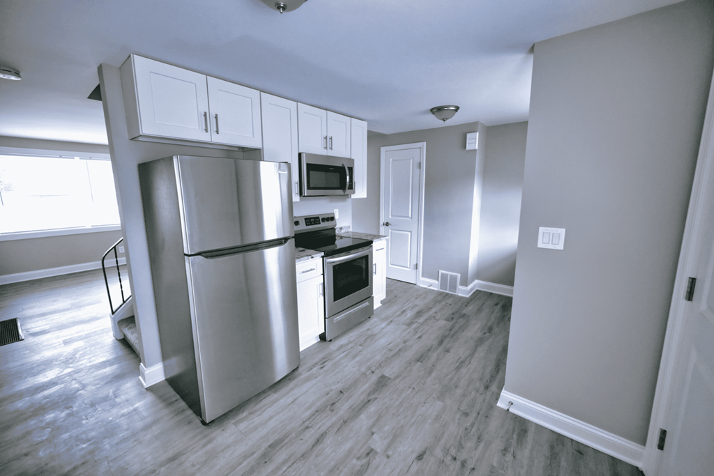 an empty kitchen with stainless steel appliances and white cabinets